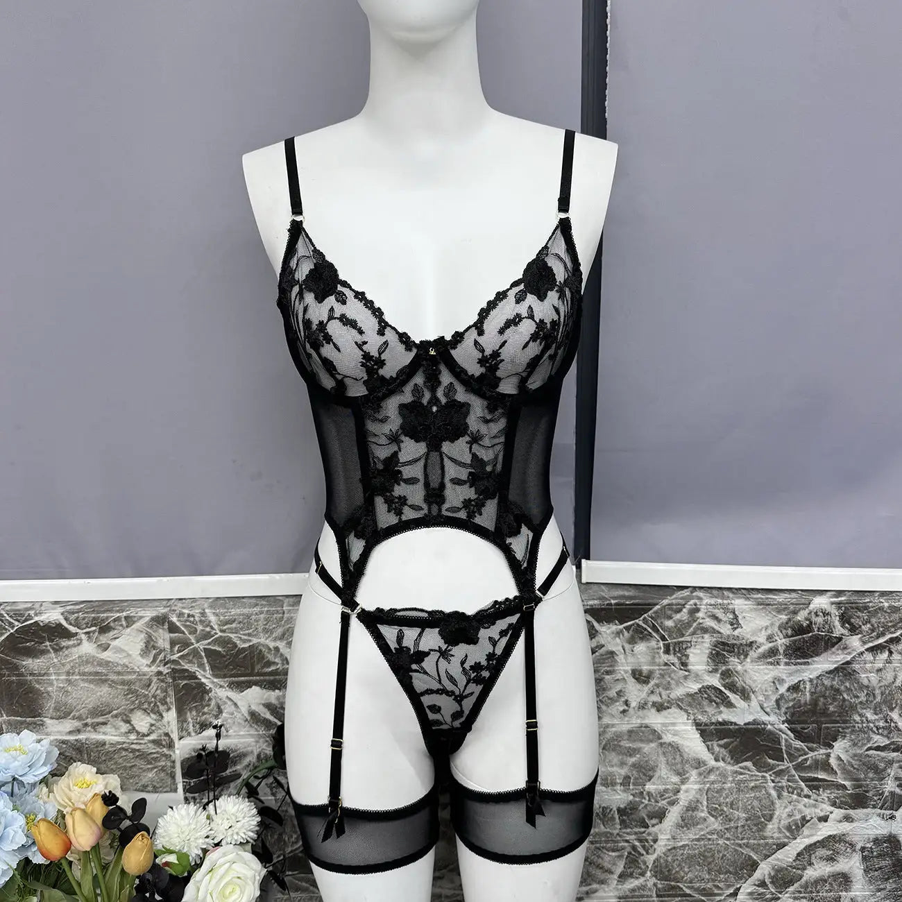 Black lace lingerie set on a mannequin against a gray background