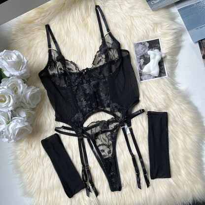 Black lace lingerie set on a fluffy white surface with flowers and books in the background.