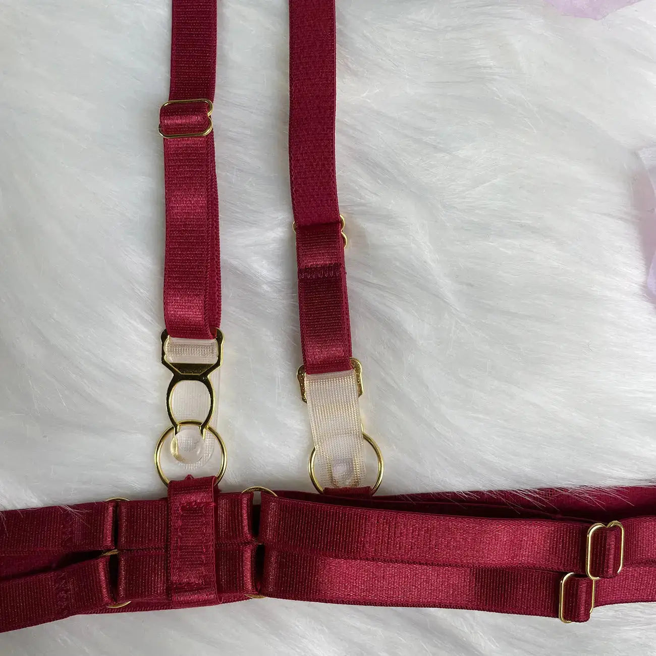 Red harness with gold hardware on a white textured background