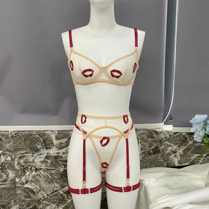 A white sheer lingerie set with red lip embroidery, including a bra, garter belt with suspenders, and matching thong, displayed on a mannequin.